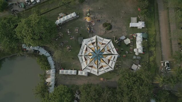 Drone takes a bird's-eye view of a coffee event in a city with tents in a public park.