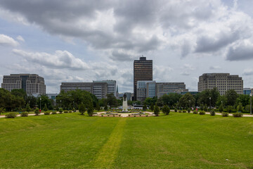 a beautiful spring landscape at Capitol Gardens with green trees, plants and grass, colorful flowers and office buildings in the skyline at the Louisiana State Capitol In Baton Rouge Louisiana USA