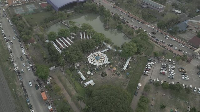 Drone takes a bird's-eye view of a coffee event in a city with tents in a public park.