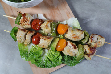 chicken kebab on skewers with vegetables on a wooden board