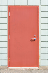 An image of an old metal exterior door with faded red paint.