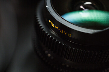 Detail of a fisheye camera lens with yellow text, specialty equipment for wide-angle shots, focus on lens edge, with a bokeh effect background.