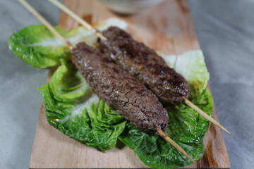 Beef kebab skewers with lettuce on a wooden board