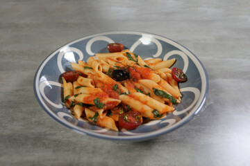 Penne pasta with tomato sauce and olives on a plate.