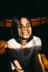 Happy brunette woman portrait in direct sunlight, indoors.