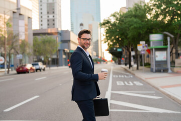 Businessman with backpack walking in city. Side view of male entrepreneur in classy suit and with...