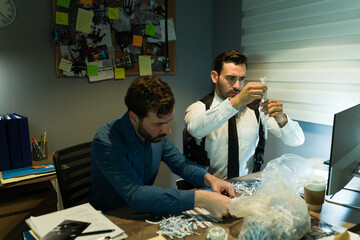 Two professional investigators putting together some shredded pieces of paper while gathering evidence at night