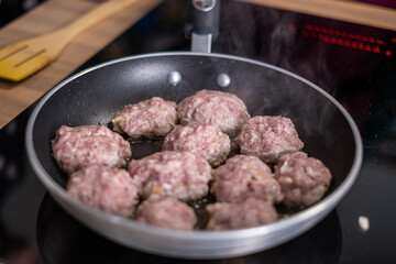 Sizzling meatballs cooking in a skillet, with steam rising, capturing the essence of home cooked comfort food in a kitchen setting.