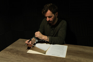 Pensive criminal handcuffed to a desk, examining immunity documents in a dimly lit room