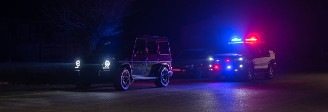 police car stands next to a car he pulled over for speeding, reaching for the driver's ID. , stock photo