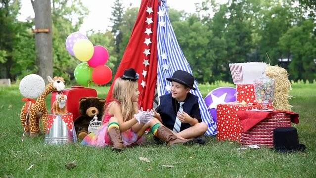 Two children are playing outside dressing up as carnival people laughing at a circus party for an imagination or creativity concept