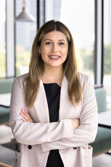 Positive confident business owner woman standing with arms crossed, keeping confidence gesture, looking at camera, smiling, posing for corporate professional female vertical portrait