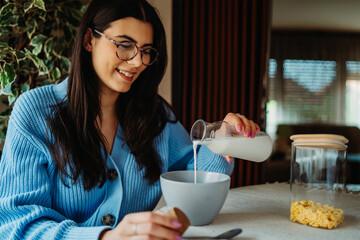 One young caucasian woman is eating breakfast at home before work
