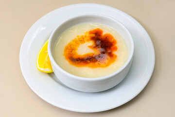 Homemade turkish soup Tavuk Suyu corbasi in a white ceramic soup plate.Turkish noodle chicken broth soup on a plate. Turkish meal (sehriyeli tavuk suyu corbasi)