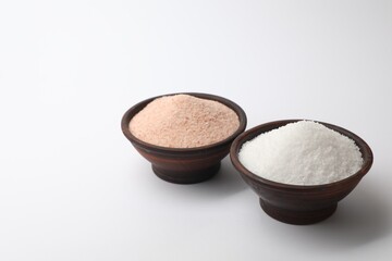 Different types of natural salt in bowls on white background, space for text