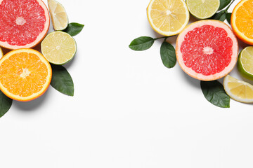 Different cut citrus fruits and leaves on white table, flat lay. Space for text
