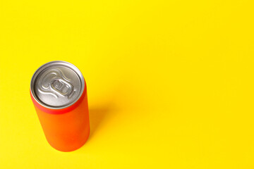 Energy drink in orange can on yellow background, above view. Space for text