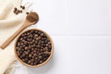 Ground and whole allspice berries (Jamaica pepper) on white tiled table, top view. Space for text