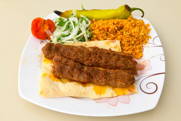 Grilled Turkish Adana, Urfa  Kebab with grilled vegetables, onion and rice on plate. Adana durum.