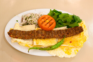 Grilled Turkish Adana, Urfa  Kebab with grilled vegetables, onion and rice on plate. Adana durum.