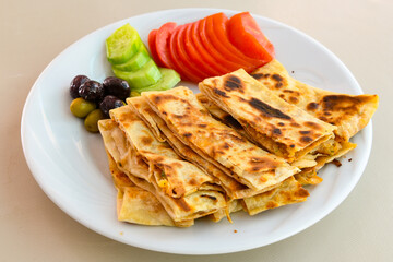 Freshly baked appetizing Turkish tortillas -Gozleme with spinach, cheese  on a wooden board. Shallow depth of  field. Handmade Turkish traditional pastries. Otlu peynirli ispanakli gozleme.