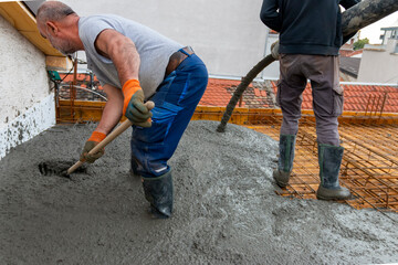 Construction workers pour concrete on rebar using concrete pump. Concreting a building plate with...