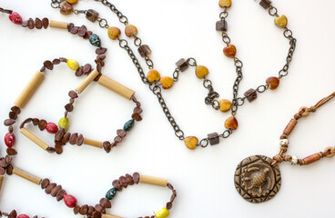 Set of Brazilian handmade necklaces on white background. Female fashion pieces with carved in wood pendant and brown and yellow beads.