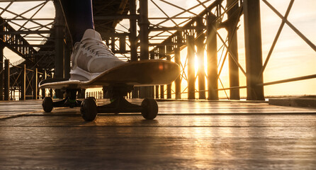 Close-up a skateboard boy on a old iron bridge at sunset. - obrazy, fototapety, plakaty