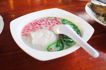 Jenang and Cendol. Traditional Javanese food (Jenang or Javanese Porridge), which is eaten with sweet soup. served in a white bowl on a wooden table.