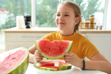 Happy little girl with slice of fresh watermelon sitting at table in kitchen