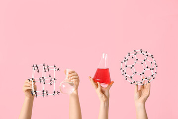 Female hands holding molecular models with filled flasks on pink background. Chemistry lesson...