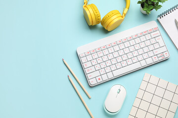 PC keyboard, mouse, headphones and stationery on blue background