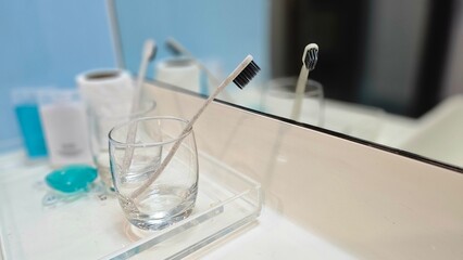 toothbrush in a hotel bathroom, hotel amenities, personal care products, clean, dental care, disposable, save, toothbrush in the glass reflect on the mirror