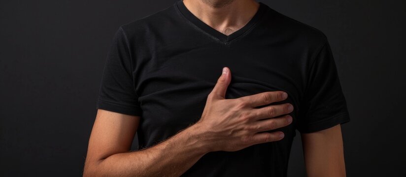 An agitated man dressed in a black shirt holds his chest with both hands, showing signs of distress or discomfort