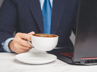 Businessman holding a cup of coffee while working at a desk.