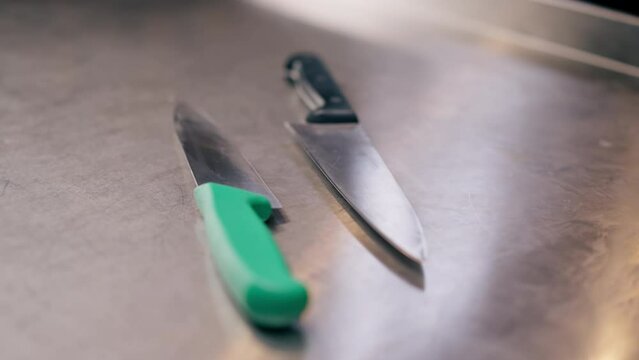 close-up of large slicing knives lying on a metal table in professional kitchen