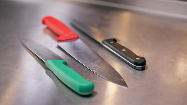 close-up of large slicing knives lying on a metal table in professional kitchen