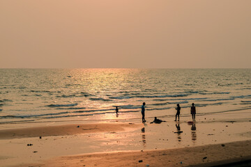 Fototapeta na wymiar Family walking on the beach at sunset