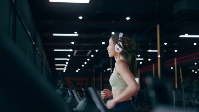 Young Asian Woman Wearing Headset Running on Treadmill - Fitness Gym Exercise