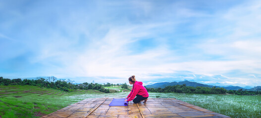 Asian woman relax in the holiday. Play if yoga. On the balcony landscape Natural Field.papongpieng...