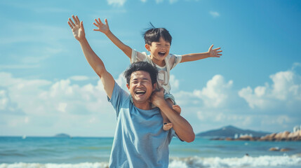 Smiling Asian Father with Son on Shoulders at the Beach with Hands Raised.