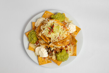 A plate of nachos with guacamole and sour cream