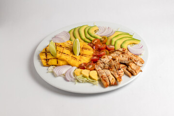 A plate of food with chicken, avocado, tomatoes, and onions