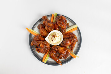 A plate of chicken wings with a side of carrots and a dipping sauce