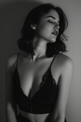 Naklejka premium In a black and white photograph, a woman with her eyes closed showcases full, luscious lips while wearing black lingerie.