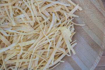 Close up of fresh unmade pasta with long strips on kitchen table, in the style of top view.