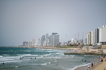 Coastline of Tel Aviv, Israel. High-rises, construction cranes, and a sandy beach line the clean...