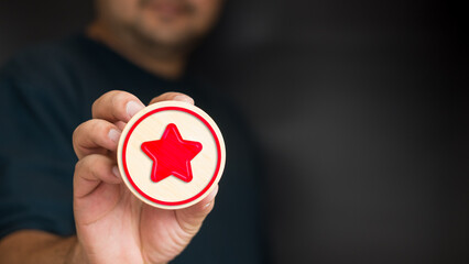 A man holding a red star icon on wood block with copy space.