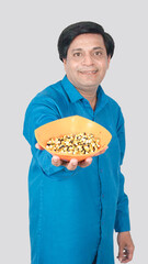 Portrait view of a front view of a young boy offering corn cob seeds bowl