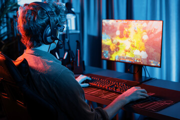 Host channel of young gaming streamer playing fighting Moba at battle arena game with multiplays team, wearing headphone on pc monitor with back side image at neon digital light modern room. Gusher. - obrazy, fototapety, plakaty